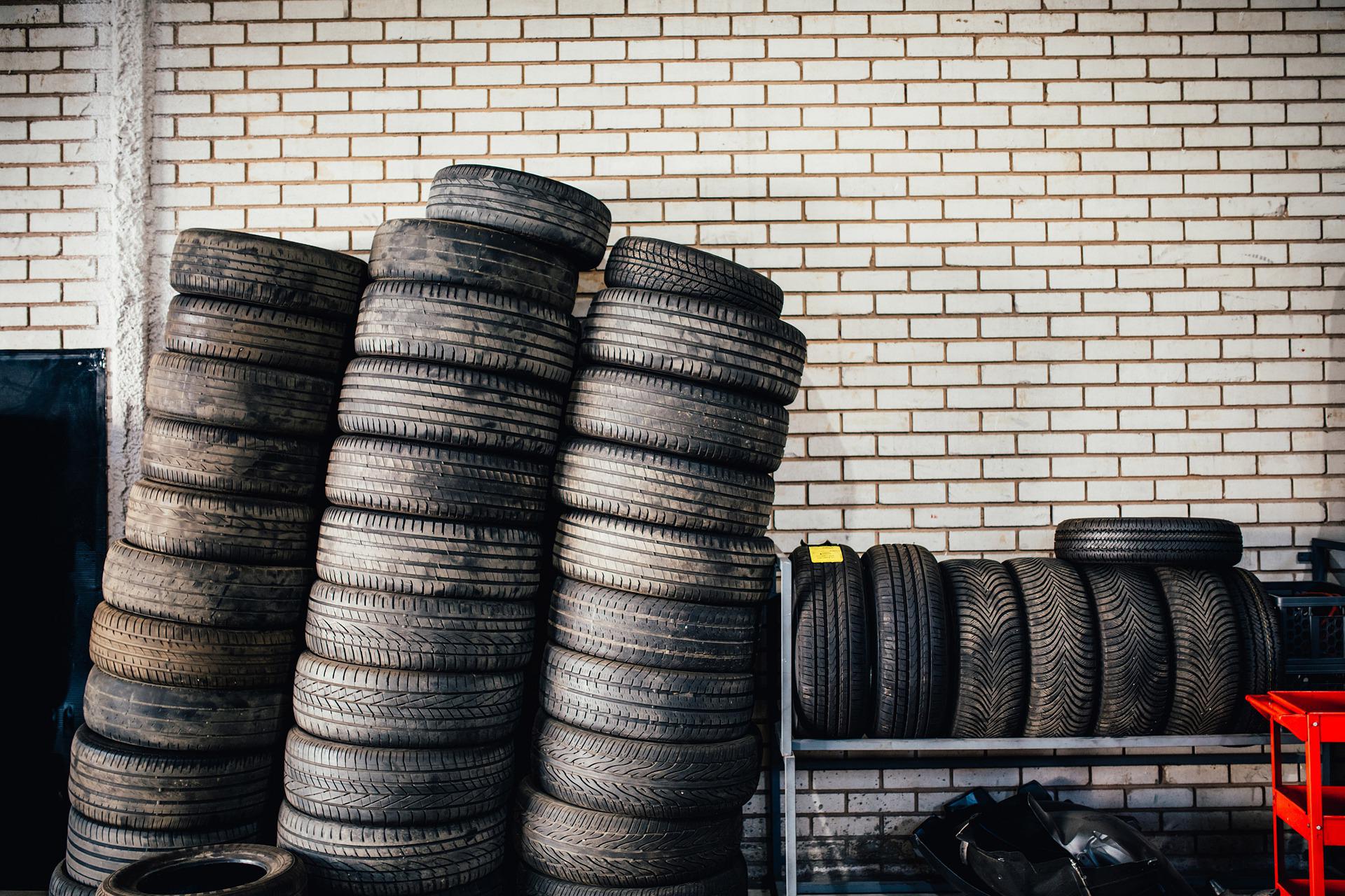 Tires lined up in a garage leaning against a brick wall.