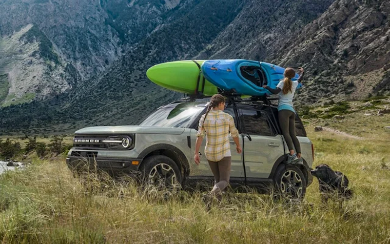 The 2024 Ford Bronco Sport carrying a kayak for two adventurous passengers in a rustic field