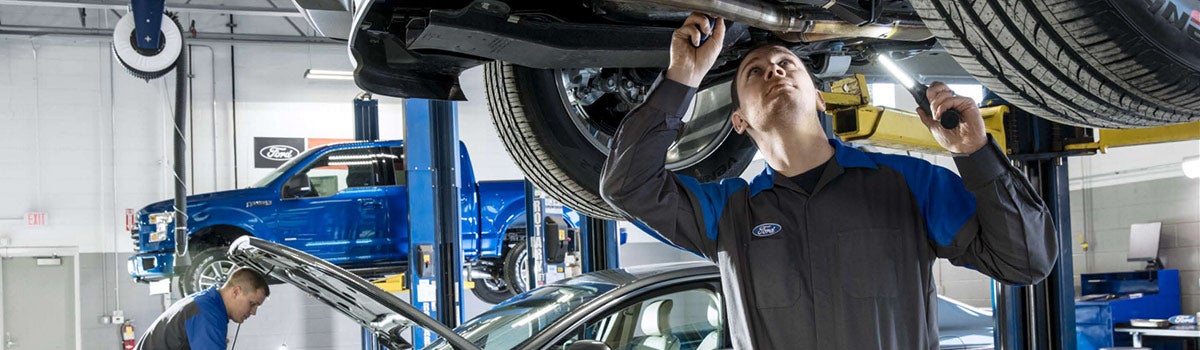 Image of a Ford technician inspecting the underside of a car.